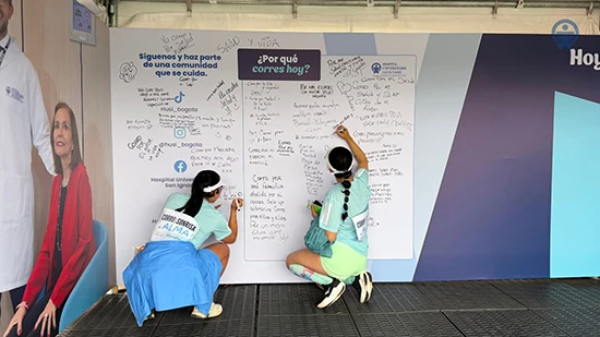 Participantes de la Media Maratón de Bogotá escriben en el mural interactivo del HUSI los motivos que los inspiran a correr, promoviendo el bienestar, la salud y el deporte responsable.